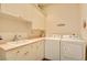 Functional laundry room with white cabinets, countertop, sink, washer, and dryer for efficient laundry tasks at 3008 Astoria Pines Cir, Las Vegas, NV 89107