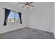 Bedroom features carpeted floors, a ceiling fan, and a large window with neighborhood views at 5589 Pico Ferrera Ct, Las Vegas, NV 89113