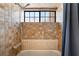 A shower area showcases neutral toned square tiles, a window, and a shower curtain at 6861 E Washington Ave, Las Vegas, NV 89110