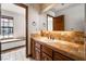 Bathroom featuring a sink with tan tiles, wooden cabinets and a window seat in the next room at 6861 E Washington Ave, Las Vegas, NV 89110
