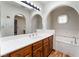 Bright bathroom with white countertop, wood cabinets, and unique decorative window above the tub at 6861 E Washington Ave, Las Vegas, NV 89110