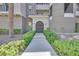 Inviting building entrance with decorative shrubs and plants leading to an arched doorway and address number at 9213 Las Manaitas Ave # 401, Las Vegas, NV 89144
