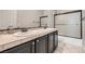 Bathroom with double sinks, tiled countertops, dark cabinets, and a shower with sliding doors at 3908 Specula Wing Dr, North Las Vegas, NV 89084