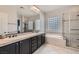 Bright bathroom featuring a dual sink vanity, glass block window, and walk-in shower with a separate tub at 3908 Specula Wing Dr, North Las Vegas, NV 89084