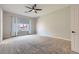 Bright bedroom with carpeted floors, neutral walls, ceiling fan, and large window at 3908 Specula Wing Dr, North Las Vegas, NV 89084