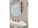 Stylish powder room featuring a pedestal sink with elegant fixtures, a round mirror, and fresh paint at 3908 Specula Wing Dr, North Las Vegas, NV 89084