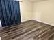Bright bedroom with dark wood-look flooring, a ceiling fan, and natural light from a large window at 6045 Riverwalk Falls St # 102, North Las Vegas, NV 89031