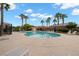 Community pool surrounded by palm trees, lounge chairs, and a secure fence for resident enjoyment at 6045 Riverwalk Falls St # 102, North Las Vegas, NV 89031