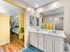 Bright bathroom featuring a double sink vanity with white cabinets and a large mirror with wood flooring at 8701 Giant Causeway Ave, Las Vegas, NV 89148