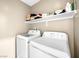 Laundry room area with modern white washer and dryer units and upper shelving at 8701 Giant Causeway Ave, Las Vegas, NV 89148