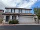 Two-story home with a tile roof, a two-car garage, and a small porch surrounded by green landscaping at 10673 Alondra Peak St, Las Vegas, NV 89183