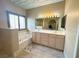 A bathroom featuring a large window with blinds, a soaking tub and a vanity with a large mirror at 1210 Country Club, Laughlin, NV 89029