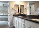 Bathroom vanity featuring dual sinks, dark countertops, white cabinets, and modern hardware with access to the bedroom at 12495 Point Sierra St, Las Vegas, NV 89138