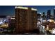 Nighttime view of a large, illuminated hotel building among other hotels and buildings on a busy city street at 125 E Harmon Ave # 2215, Las Vegas, NV 89109