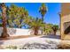 Landscaped backyard with a concrete patio, a rock garden, and mature trees at 2105 Harbor Cliff Dr, Las Vegas, NV 89128