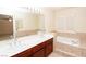 Bathroom with double sinks, a large mirror, and a soaking tub with tile surround at 2105 Harbor Cliff Dr, Las Vegas, NV 89128