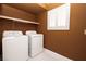 Neat laundry area showcasing a washer, dryer, white shutters, and shelf for storage at 2105 Harbor Cliff Dr, Las Vegas, NV 89128