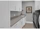 Bright laundry room featuring modern cabinets, stone countertops, and stainless steel washer and dryer at 4430 Angelo Rosa St, Las Vegas, NV 89135