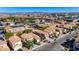 An aerial shot features a residential area with terracotta roofed homes, palm trees, and city views under a clear sky at 5438 Jacobs Field St, Las Vegas, NV 89148