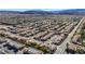 High angle shot of a housing development with orderly rows of houses, ample green spaces, and mountain views at 5438 Jacobs Field St, Las Vegas, NV 89148