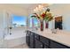 Bright bathroom featuring double sinks, a large mirror, soaking tub and large window at 5556 Cornadelo Range Rd, Las Vegas, NV 89113