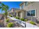 View of the townhome exterior featuring a paved walkway, stone landscaping, and a quaint covered entrance at 5730 Sky Pointe Dr # 104, Las Vegas, NV 89130
