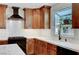 Kitchen featuring a gas range and hood, wood cabinets, a bright window over the sink, and marble countertops at 619 D Avenue, Boulder City, NV 89005