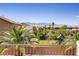 A backyard view from a balcony with a green lawn, playground, palm trees, other homes, and distant mountains at 6489 Crest Estates St, Las Vegas, NV 89131