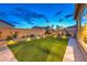 A well-maintained backyard at night featuring artificial turf, brick retaining wall, and landscape lighting at 8445 S Tenaya Way, Las Vegas, NV 89113
