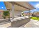 Close-up of covered outdoor kitchen with stone countertops, grill, and manicured landscaping at 8445 S Tenaya Way, Las Vegas, NV 89113