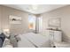 Staged bedroom with dresser, artwork, and large window letting in natural light and view at 9277 Ardoa Ave, Las Vegas, NV 89148