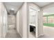 Bright hallway leading to rooms with neutral paint, plush carpeting, and access to bathroom with vanity area at 9277 Ardoa Ave, Las Vegas, NV 89148
