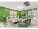 Bright living room featuring a white sofa, green accent wall, and stylish decor at 9277 Ardoa Ave, Las Vegas, NV 89148