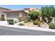 Frontal view of tan two-story home with mature trees and shrubs at 932 Tafalla Ct, Las Vegas, NV 89138