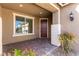 Inviting entrance with a brown front door, brick flooring, and decorative plants at 9519 Wild Valley Ave, Las Vegas, NV 89148