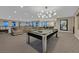 A recreation room with a pool table, sectional sofa, and modern chandelier creates the perfect entertaining space at 10 Olympia Outlook Dr, Las Vegas, NV 89141