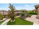 Backyard featuring manicured lawn, walkway, stone planters with lush greenery, and privacy fencing at 10305 Turia Gardens Rd, Las Vegas, NV 89135
