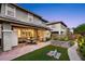 Backyard features patio with seating, landscaped garden, lush green lawn, and adjacent home at 10305 Turia Gardens Rd, Las Vegas, NV 89135