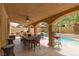 Inviting covered patio features a dining area, outdoor kitchen, and bar seating overlooking the pool at 10325 Falls Church Ave, Las Vegas, NV 89144