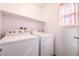 Bright laundry room features a white washer and dryer and a shelf for organizing supplies at 1035 Spotted Saddle St, Henderson, NV 89015