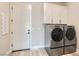 Well-lit laundry room features cabinets above washer and dryer and door to the side at 138 Crimson Cactus Ave, Henderson, NV 89011