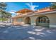 Charming exterior view of home featuring a three-car garage, arched entryway, and a red-tile roof at 1410 E Serene Ave, Las Vegas, NV 89123