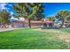 Expansive front yard features a large shade tree, lush green lawn, and a charming home with a red-tile roof and a three-car garage at 1410 E Serene Ave, Las Vegas, NV 89123