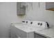 Bright laundry room features a washer and dryer with overhead shelving for convenient storage solutions at 1410 E Serene Ave, Las Vegas, NV 89123