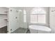 Modern bathroom with a glass-enclosed shower, soaking tub, and large window, creating a luxurious and serene space at 191 Reed Ln, Henderson, NV 89074