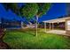 A view of a backyard featuring a covered patio area, trampoline, and mature tree, creating a peaceful outdoor space at 1933 Coralino Dr, Henderson, NV 89074