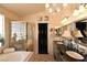 Bright bathroom featuring a chandelier, soaking tub, glass-enclosed shower, and dual sink vanity with dark countertop at 2305 Flower Spring St, Las Vegas, NV 89134