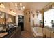 Bright bathroom features a chandelier, soaking tub, and double sink vanity with black countertop at 2305 Flower Spring St, Las Vegas, NV 89134