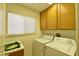 Functional laundry room featuring washer, dryer, sink, and ample storage cabinets at 2305 Flower Spring St, Las Vegas, NV 89134
