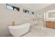 Bright bathroom featuring a soaking tub, glass enclosed shower with gold hardware, and a light wood vanity at 2316 Prometheus Ct, Henderson, NV 89074